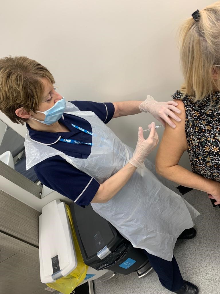 Nurse in PPE giving a woman an injection